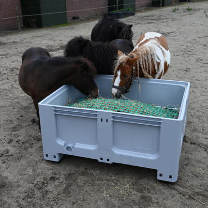 Grijze lage slowfeeder XXL gevuld met hooi, gebruikt door 3 pony’s