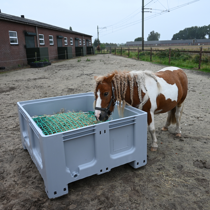 Pony die comfortabel hooi eet uit een lage grijze slowfeeder XXL